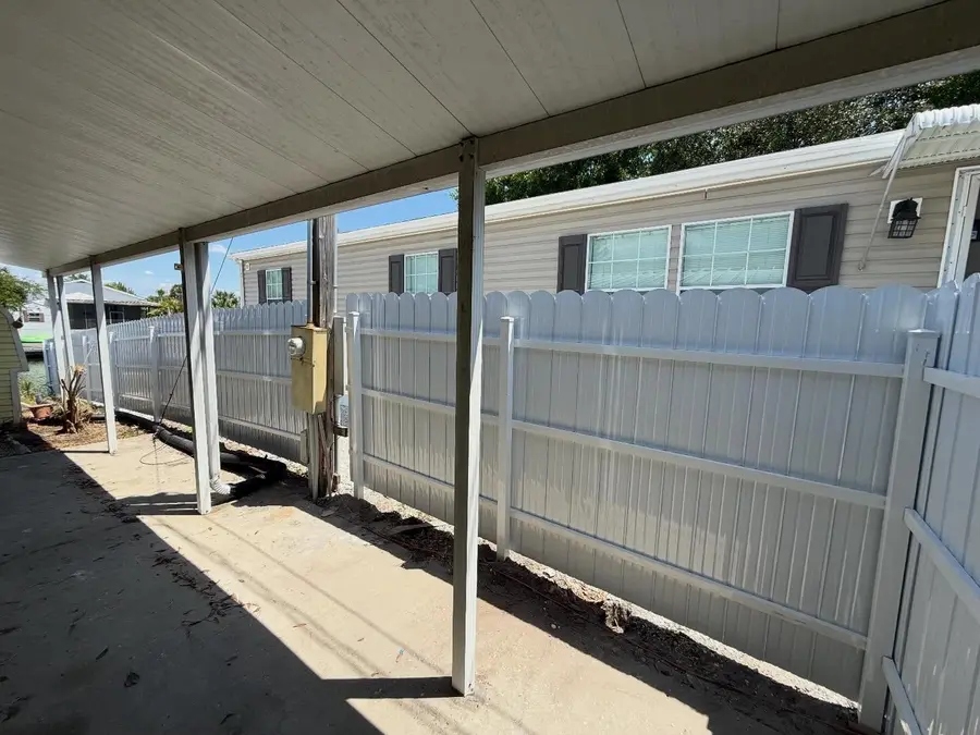 Fence company Daytona Beach, FL — white vinyl picket fence beside a covered carport