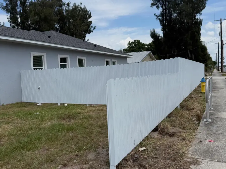 Fence company Sarasota, FL — white vinyl fence along a corner lot sidewalk