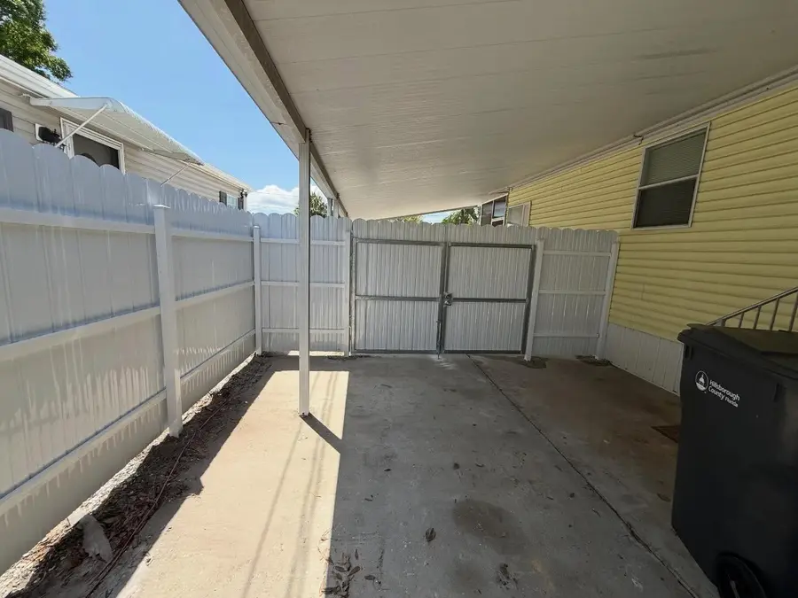 Fence company Fort Myers, FL — white vinyl gate installed under a carport