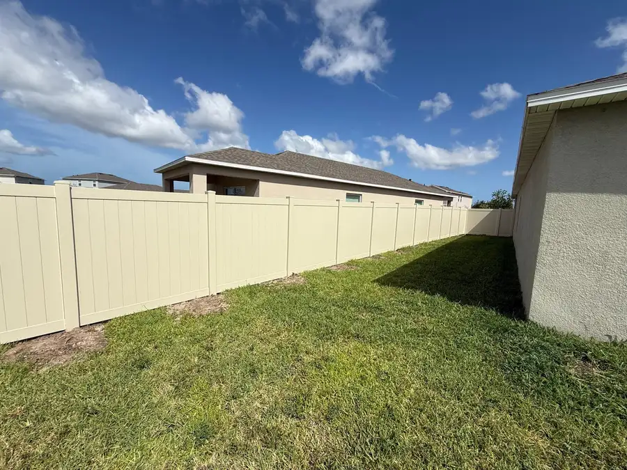 Tan vinyl privacy fence installed along a Tampa, FL backyard